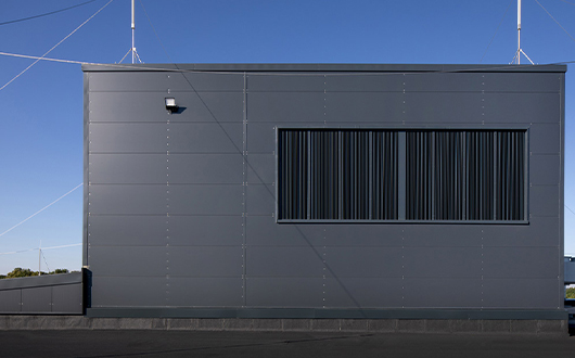 Moderne Industriefassade eines Gebäudes mit grauer Verkleidung und strukturierten Metallelementen